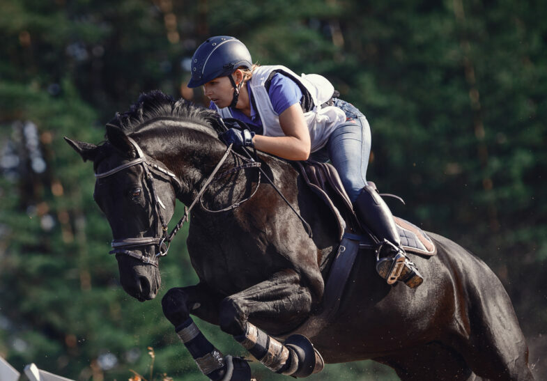 Attractive rider woman jumping over obstacle